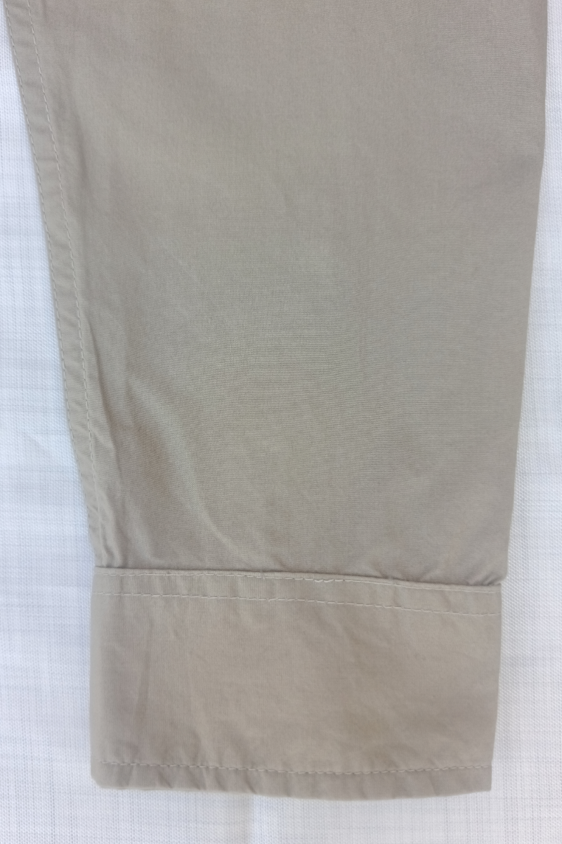 Close-up of a front side cuff beige shirt with button details on a white background