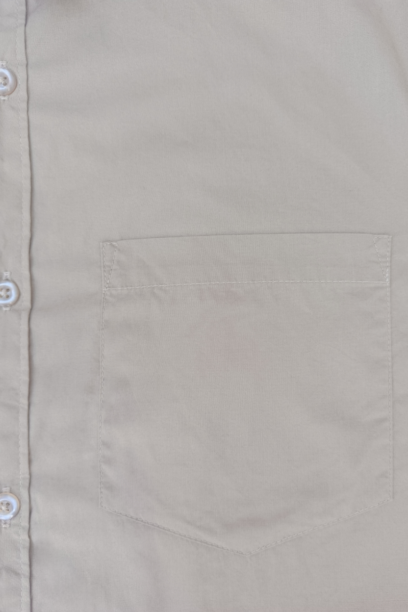 Close-up of a beige shirt with a pocket and button details