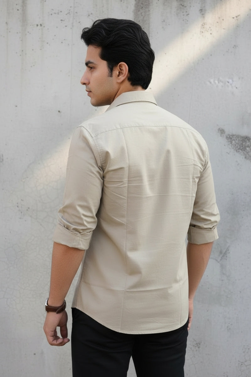 Men's beige relaxed fit cotton shirt with chest pocket back view by Quiet Soul worn by model against grey concrete background