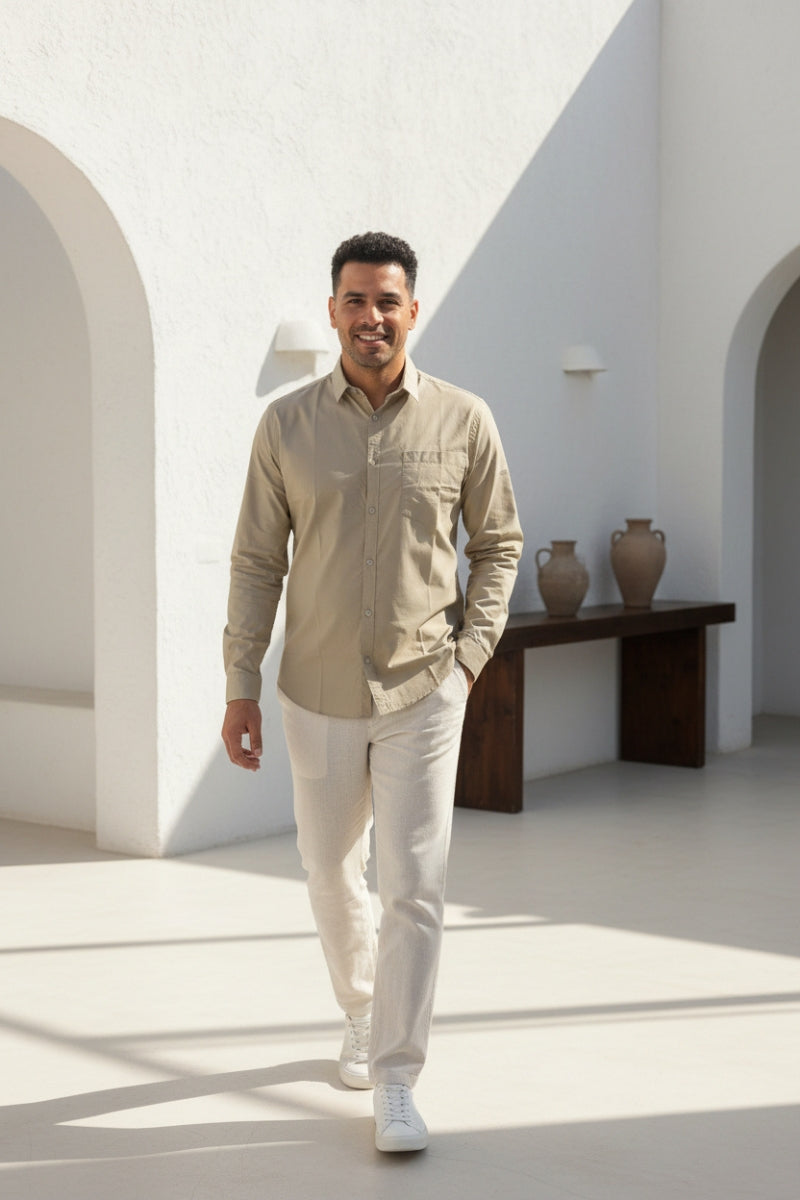 Men's beige relaxed fit cotton shirt with chest pocket front view walking by Quiet Soul worn by model inside house background