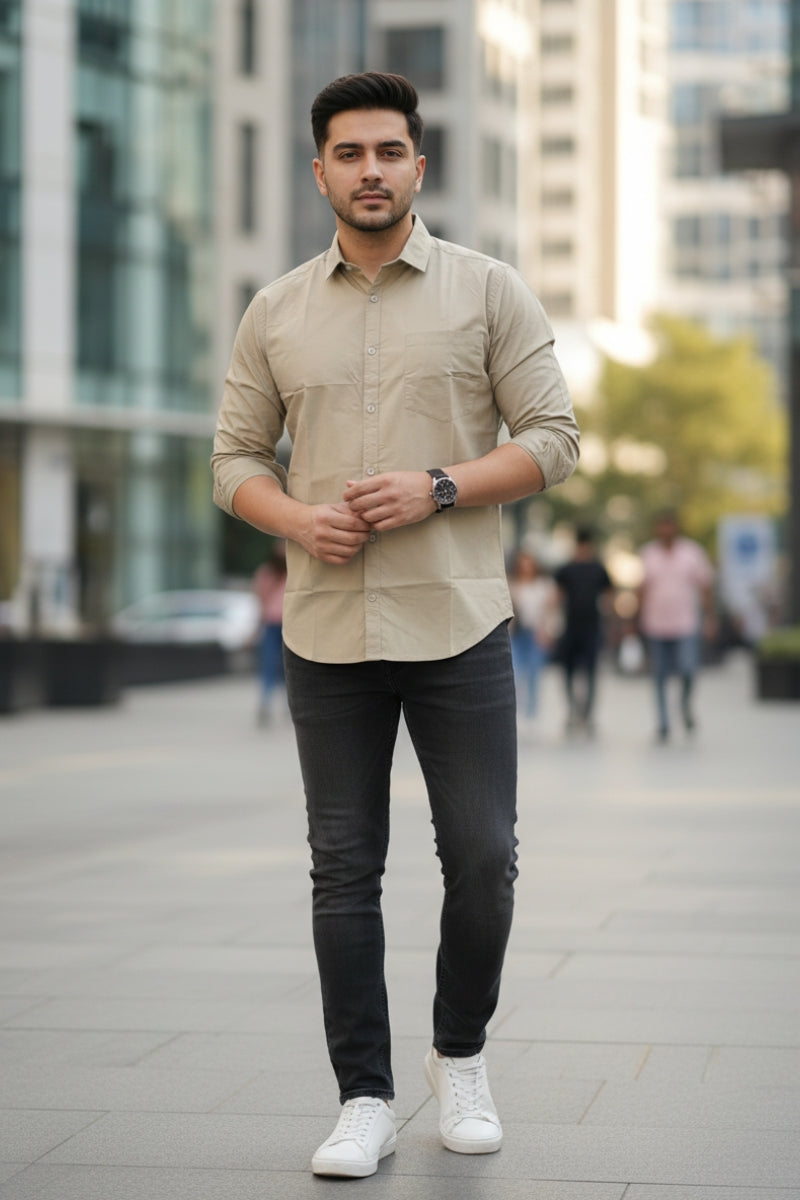 Men's beige relaxed fit cotton shirt with chest pocket front view walking by Quiet Soul worn by model against multi story building background